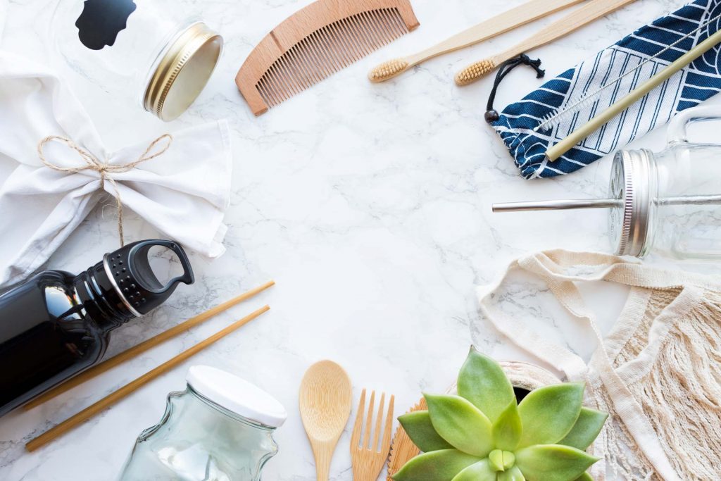 Sustainable living ideas flatlay with wooden utensils, succulent, and glass bottles