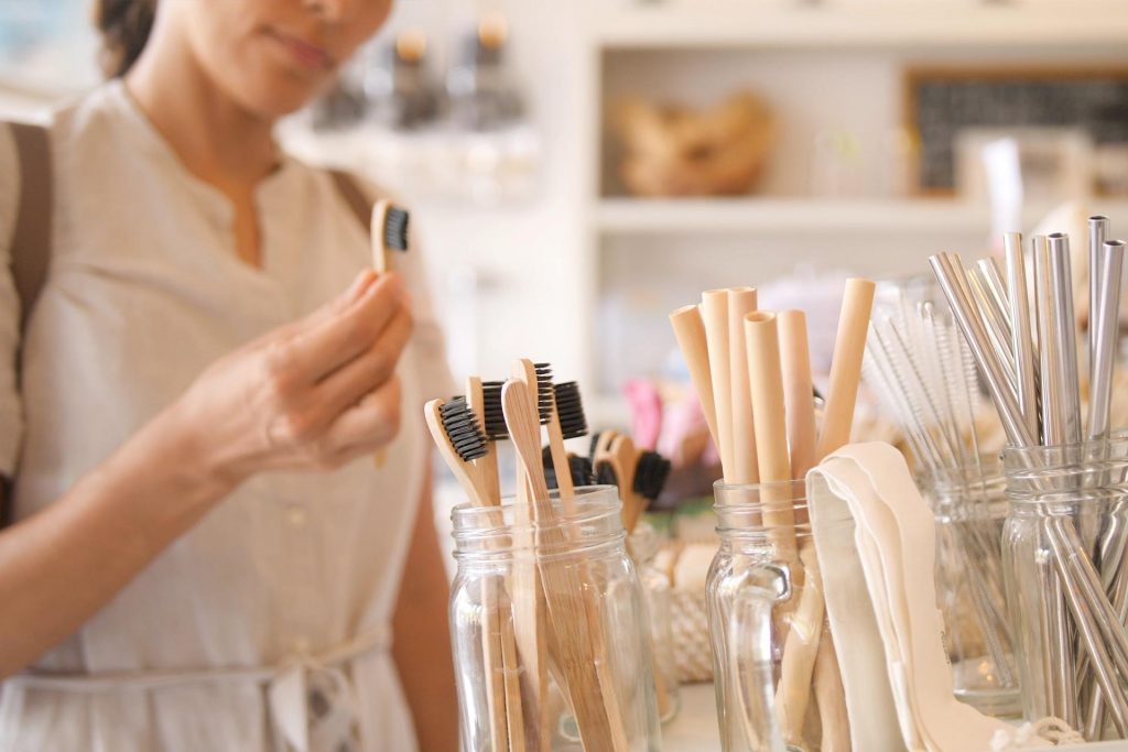 Woman shopping for sustainable living products including toothbrushes and straws