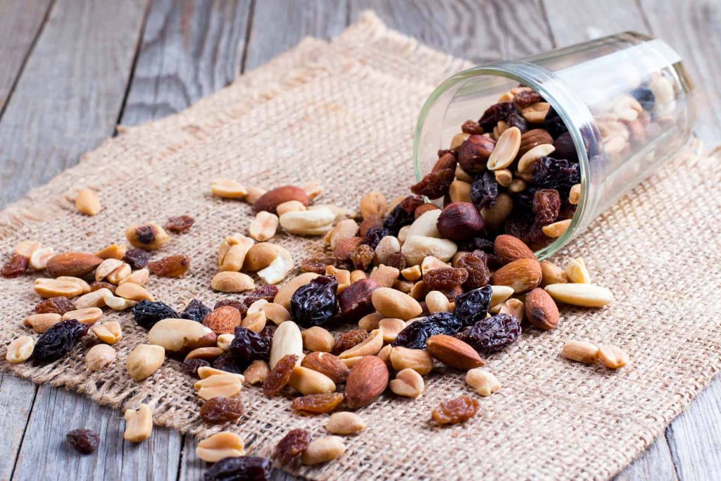 Popular zero waste snacks of nuts and dried fruit spilling from jar onto napkin