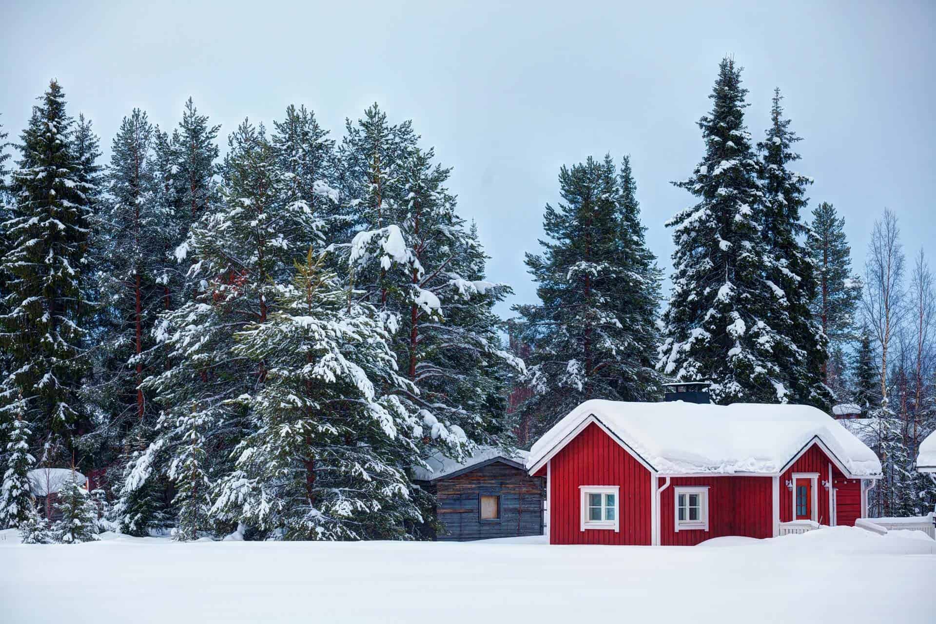 Red cottage in snowy forest landscape, an idyllic place to move to live a simple life.