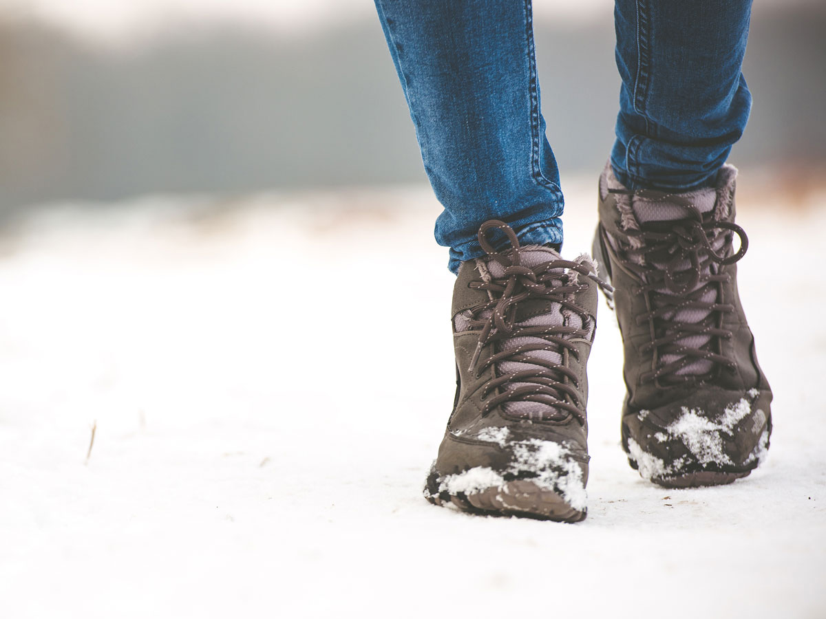 Person wearing sustainable winter boots walking through snowy field.