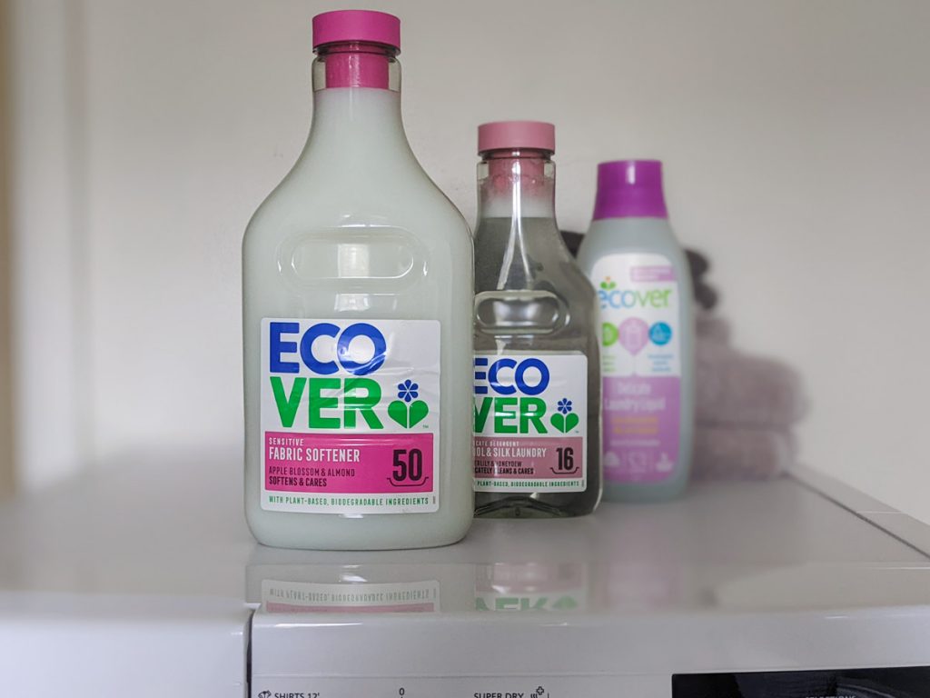 Three bottles of eco friendly fabric softener and detergent sitting on top of white dryer.