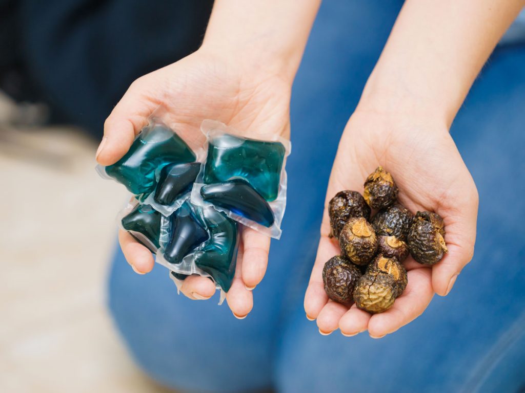 Woman holding laundry detergent pods and soap nuts.