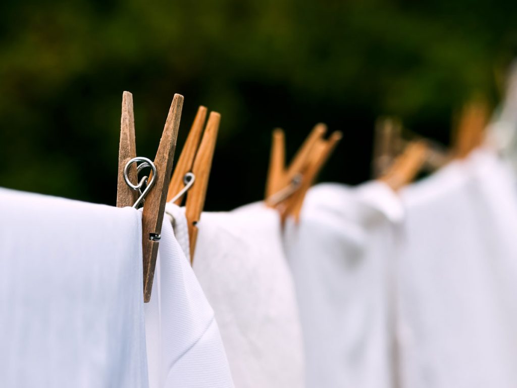White sheets hanging on laundry line outside.