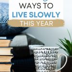Table with mug, stack of books, and jute mat, with text overlay - "14 easy ways to live slowly this year".